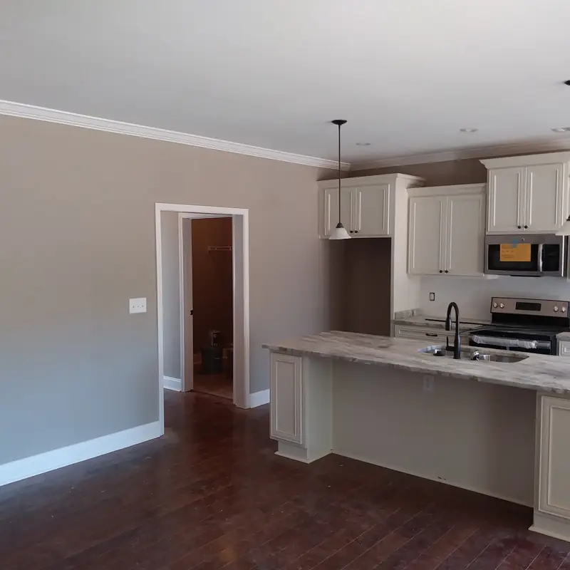 Open kitchen and living room in greige with cream cabinets and white crown
