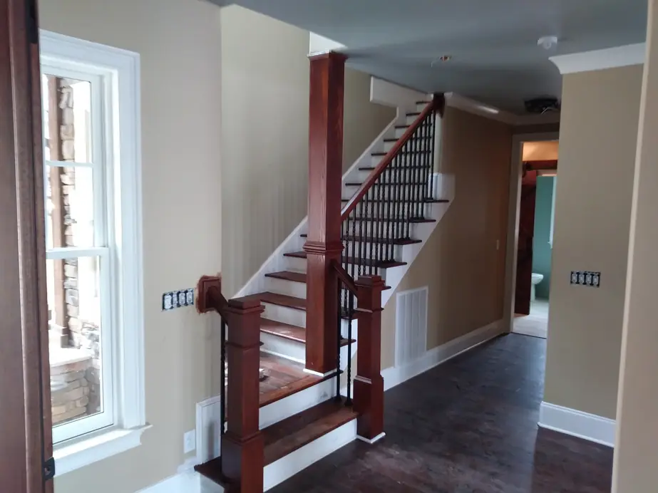 Stair hall with white painted risers, khaki walls and white baseboard